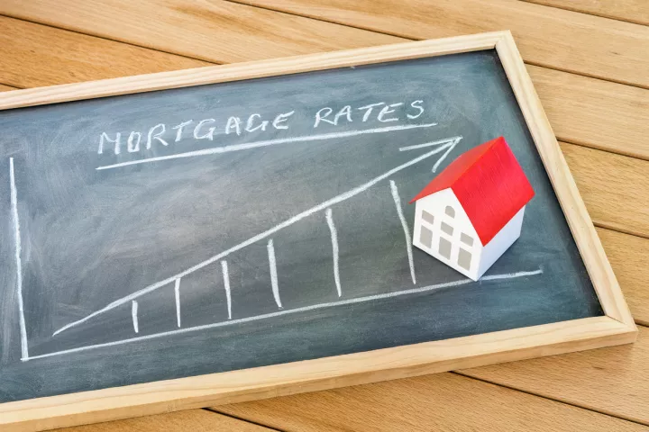 Image of a chalkboard with increasing interest rates and a house