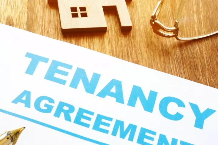 An unsigned tenancy agreement sits on a wooden table