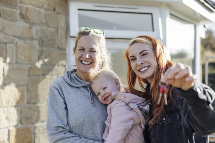 Women and child smiling holding a key